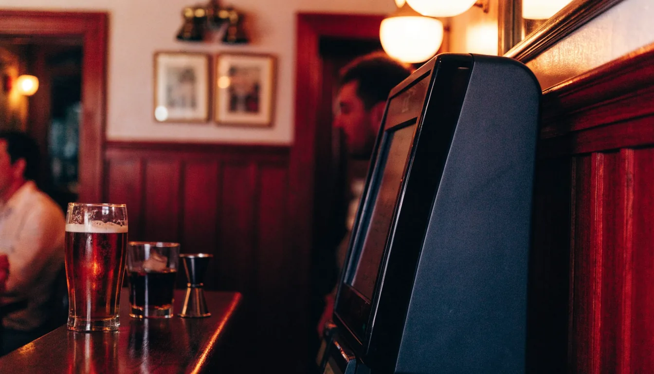 Traditional British pub interior with a slot machine terminal and pint of ale on the counter